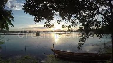 漂浮的渔夫`停泊在湖湾的木船上日落。